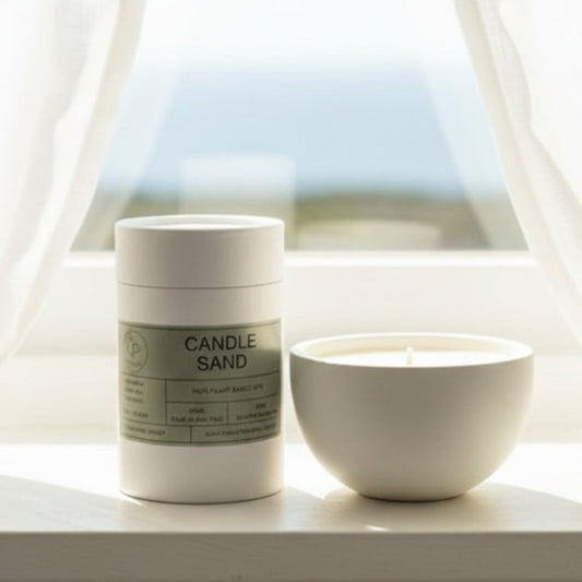 Container labeled 'Candle Sand' next to a small white candle on a wooden surface.