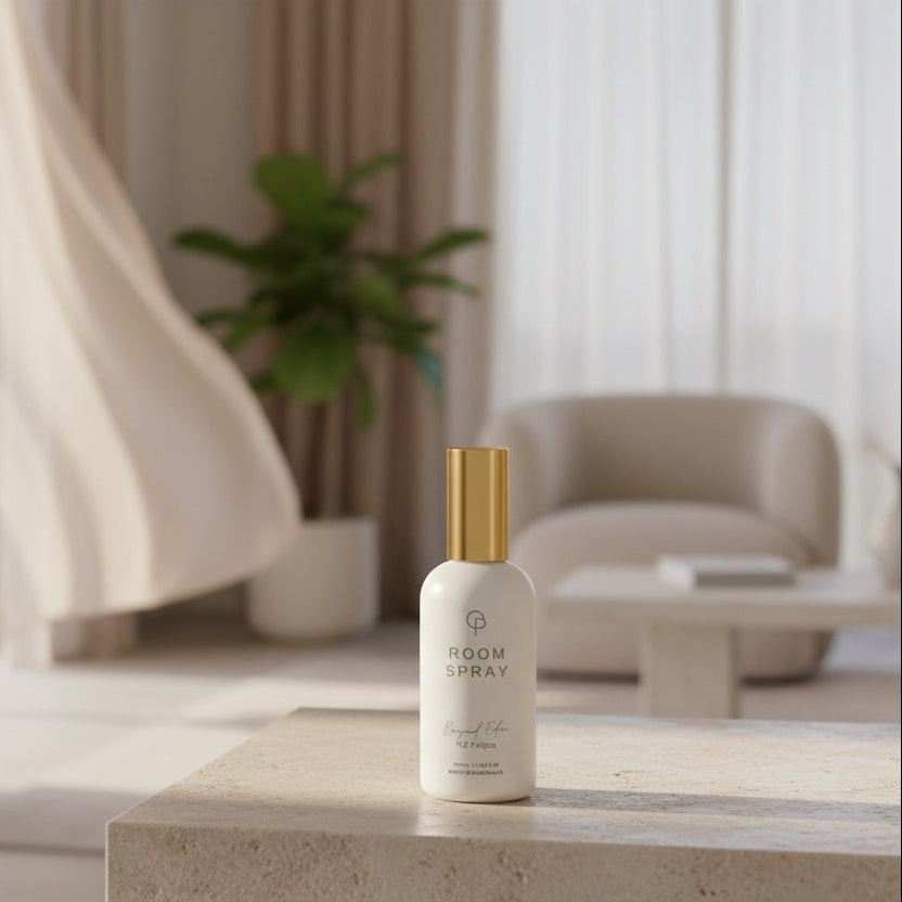 White bottle with gold cap on a stone surface in a modern room with large windows and a plant.