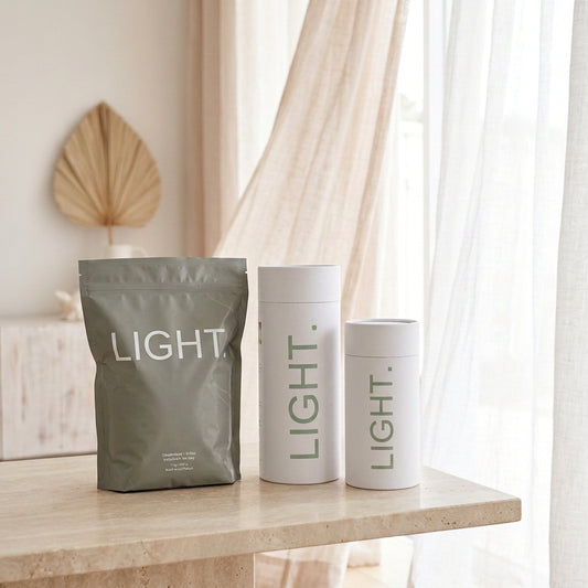 Bags and two canisters of packed CandleSand Wax on a granite bench top with curtains blowing in the background